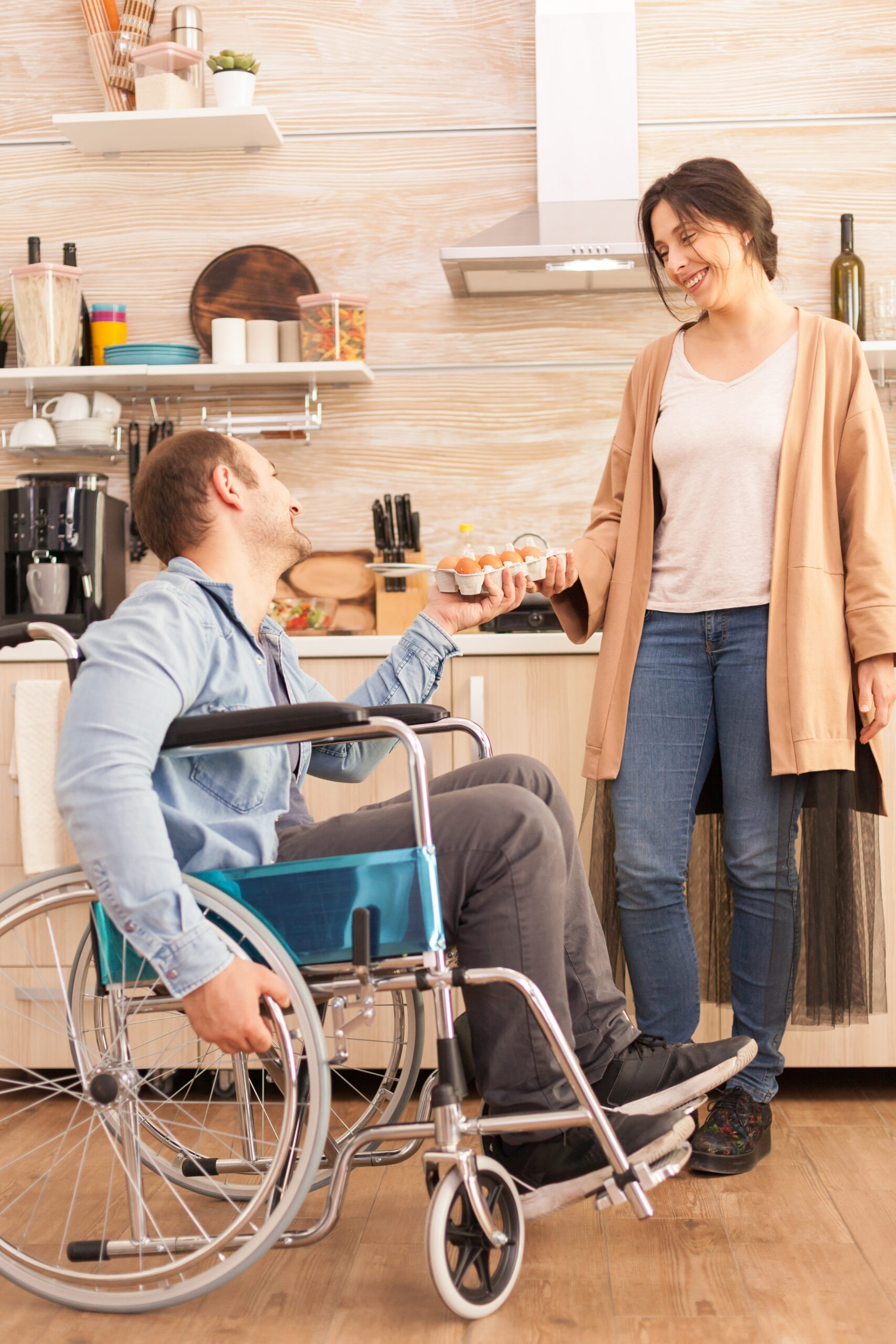 Homme en fauteuil roulant préparant un repas dans sa cuisine avec un proche